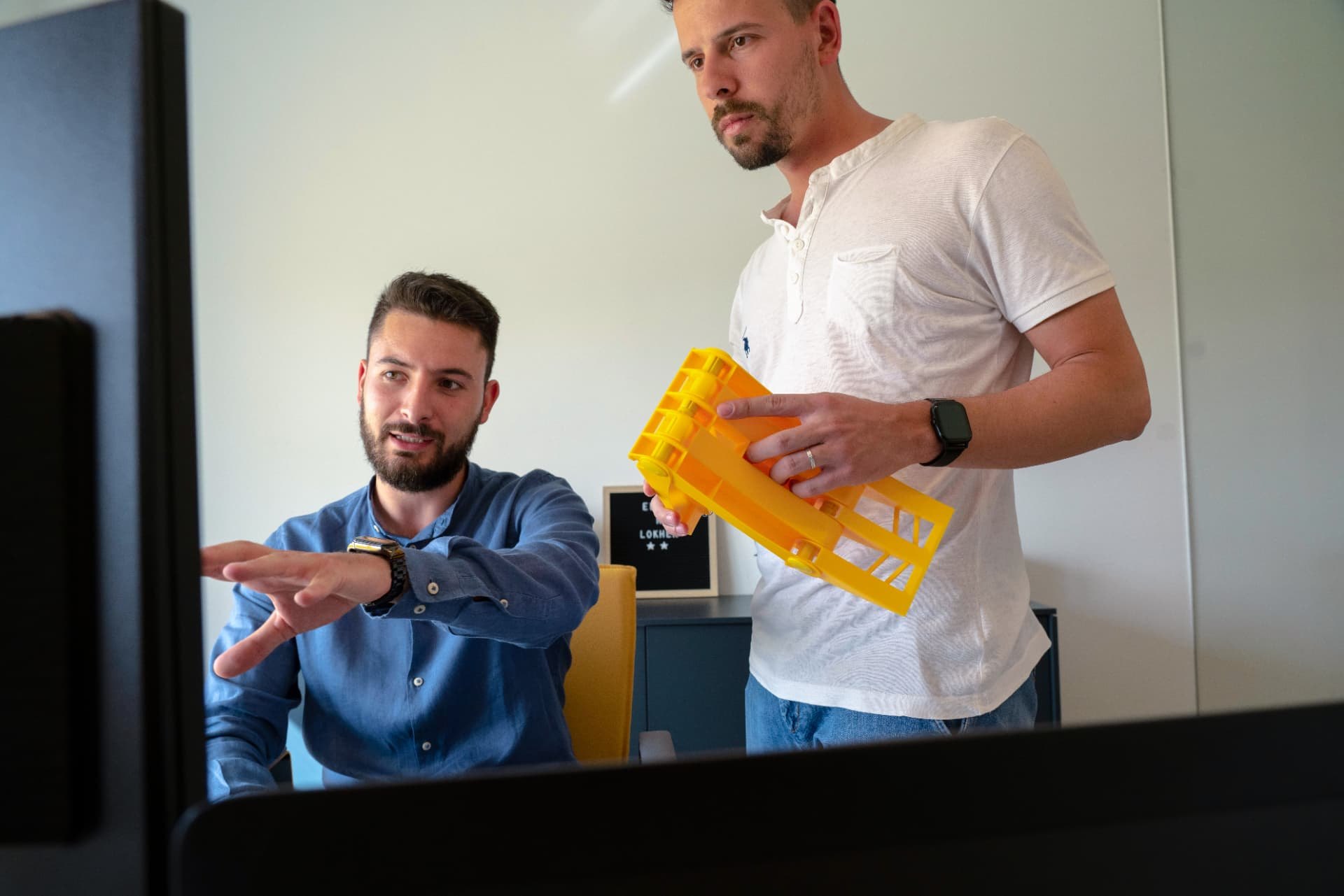 Due tecnici Lokhen Group esaminano un componente stampato in 3D di colore giallo